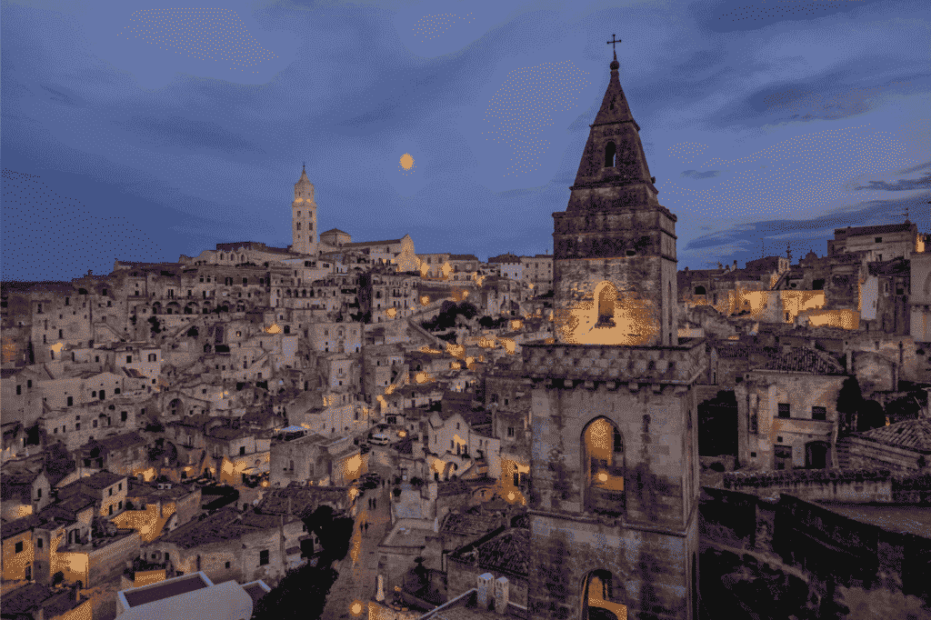 Blick auf Matera bei Nacht mit Glockenturm von San Pietro Barisano im Vordergrund