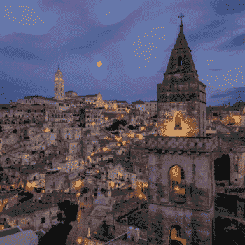 Blick auf Matera bei Nacht mit Glockenturm von San Pietro Barisano im Vordergrund