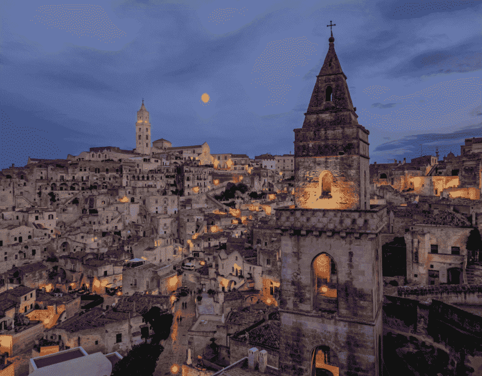 Blick auf Matera bei Nacht mit Glockenturm von San Pietro Barisano im Vordergrund
