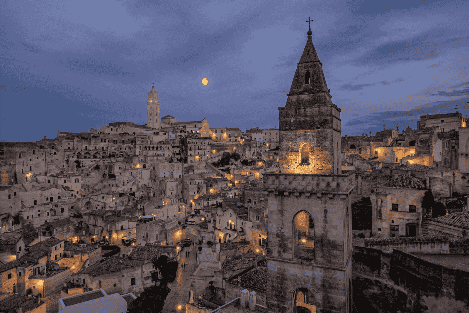 Blick auf Matera bei Nacht mit Glockenturm von San Pietro Barisano im Vordergrund
