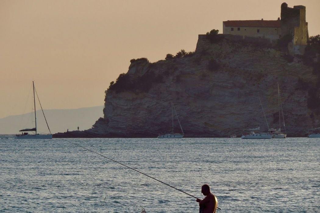 Angler vor Klippe zum Sonnenuntergang in Castiglione della Pescaia
