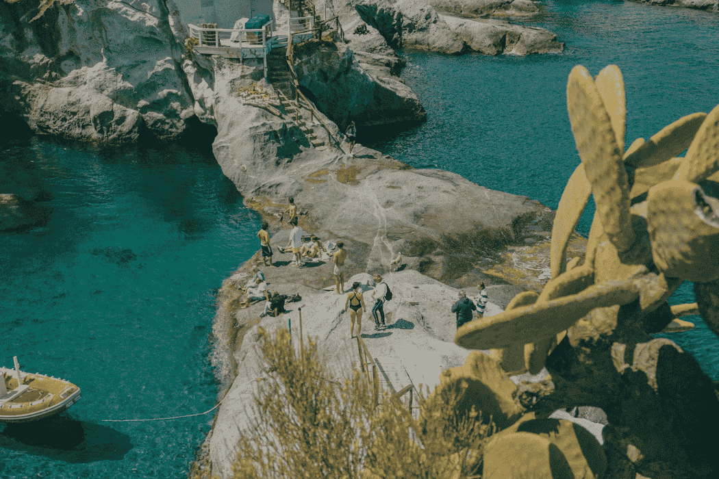 Blick auf Felsen mit Menschen in Badesachen und blaues Meer in Ponza