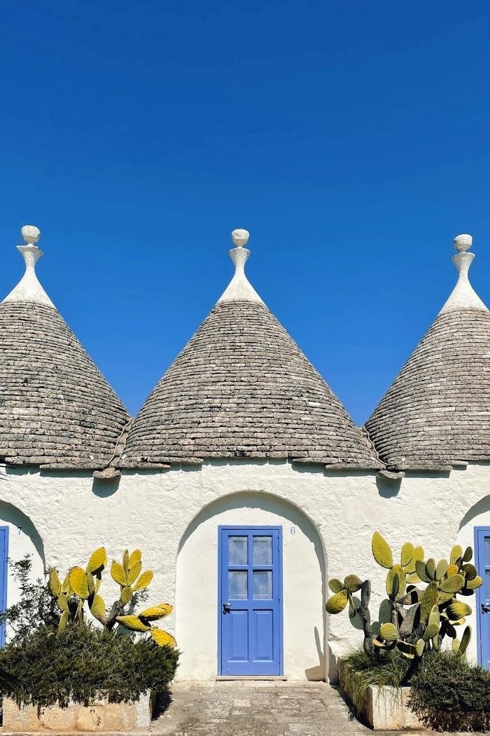 Blick auf Trulli in Apulien mit blauen Haustüren