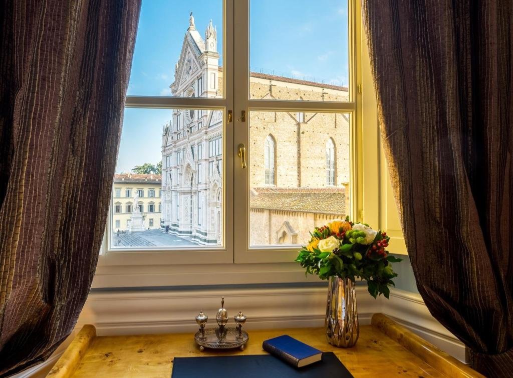 Fenster mit dunklen Vorhängen links und rechts mit Blick auf Basilika Santa Croce in Florenz