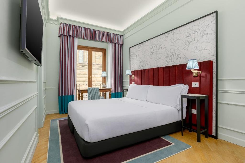 Hotelzimmer mit vertäfelten Wänden, Doppelbett und sichtbarem Palazzo vor dem Fenster in Florenz