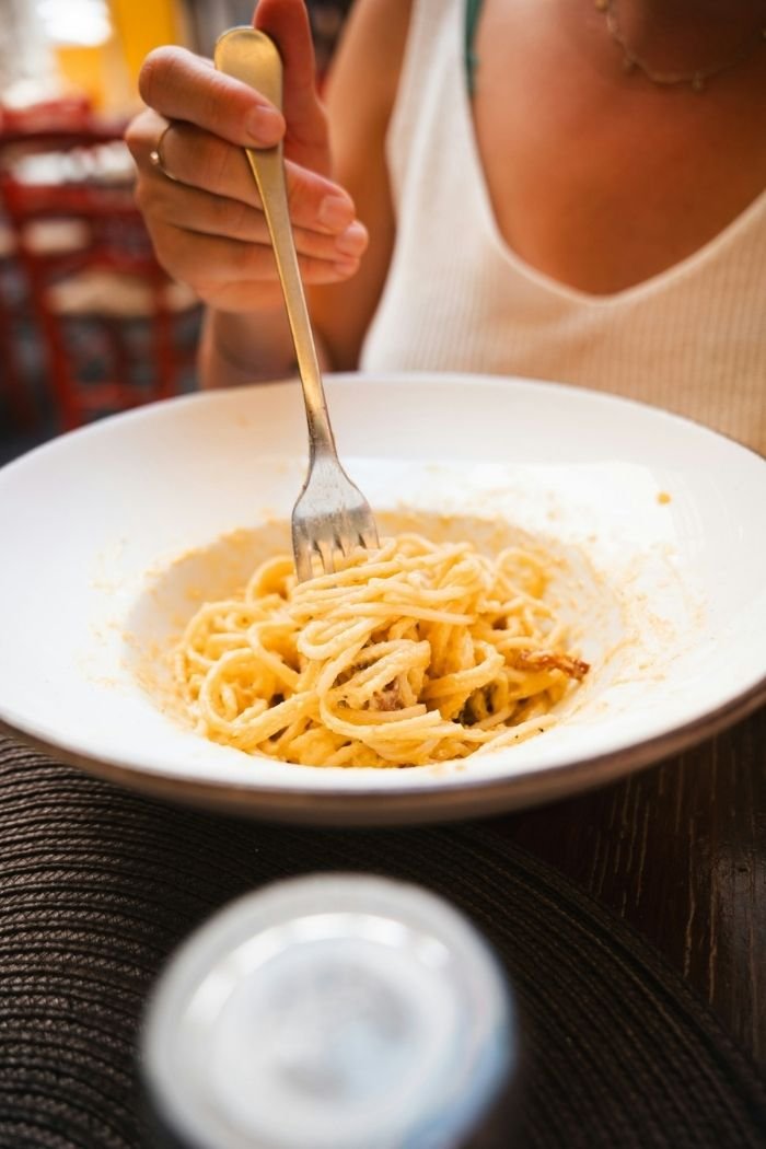 Teller mit Spaghetti carbonara mit Gabel und Frau in Rom