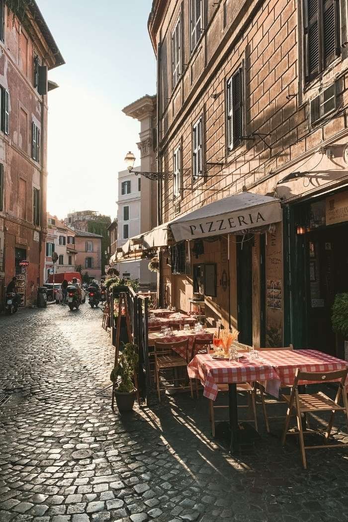 Blick auf Gasse mit Kopfsteinpflaster und Pizzeria in Trastevere in Rom