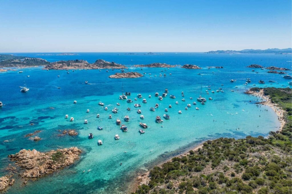 Strand in Sardinien mit türkisblauem Wasser und Booten
