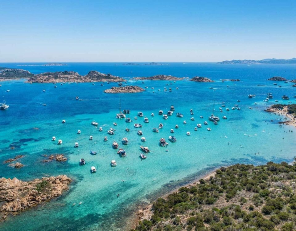 Strand in Sardinien mit türkisblauem Wasser und Booten