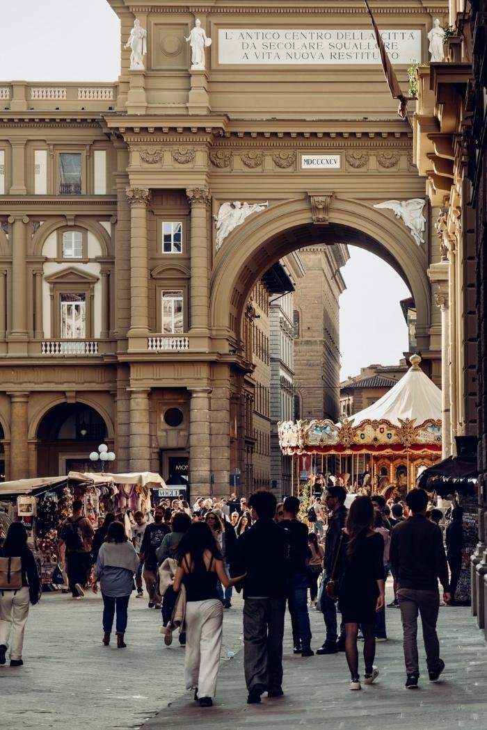 Menschen auf der Piazza della Repubblica in Florenz mit Karussell und Bogen