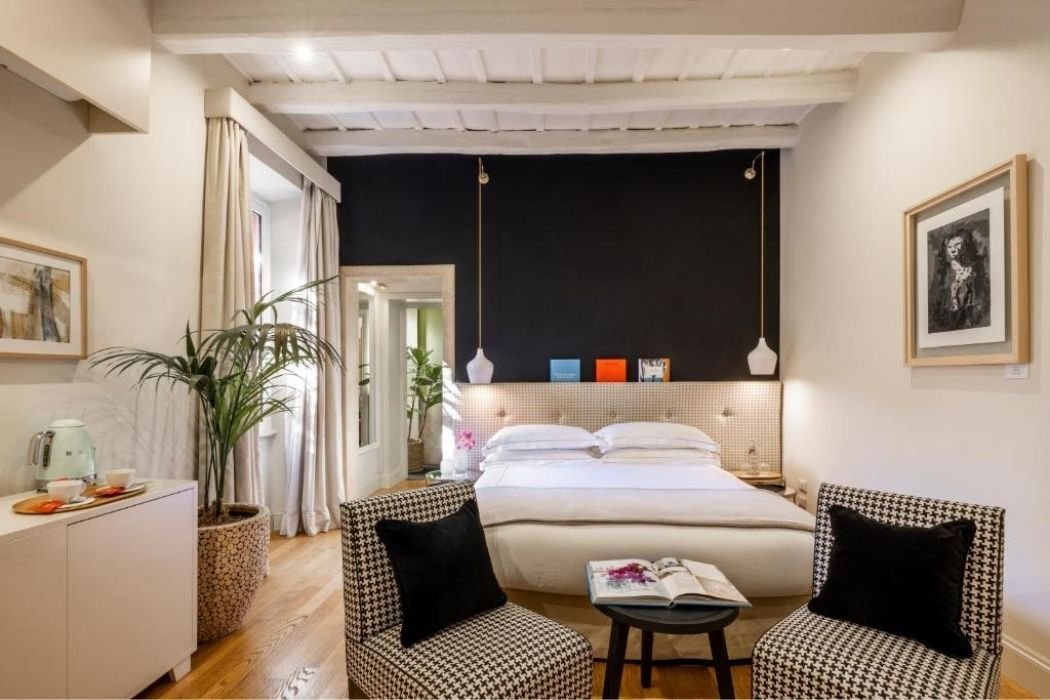 Modernes Hotelzimmer mit Doppelbett, zwei Sesseln und schwarzer Wand