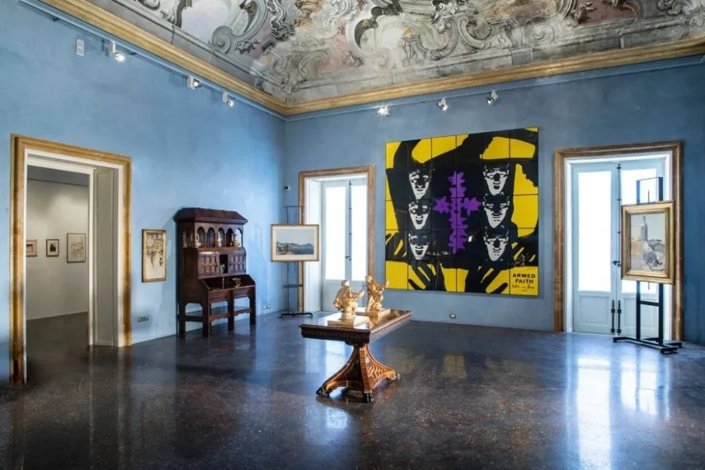 Saal mit hellblauen Wänden und goldenem Stuck mit moderner und alter Kunst im Palazzo Butera