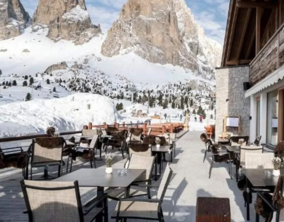 Hotel im Schnee in den Dolomiten mit Terrasse und Sitzplätzen